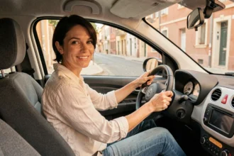 Femme conduisant une voiture sans permis à Béziers, vue de l'intérieur avec façades méditerranéennes en arrière-plan